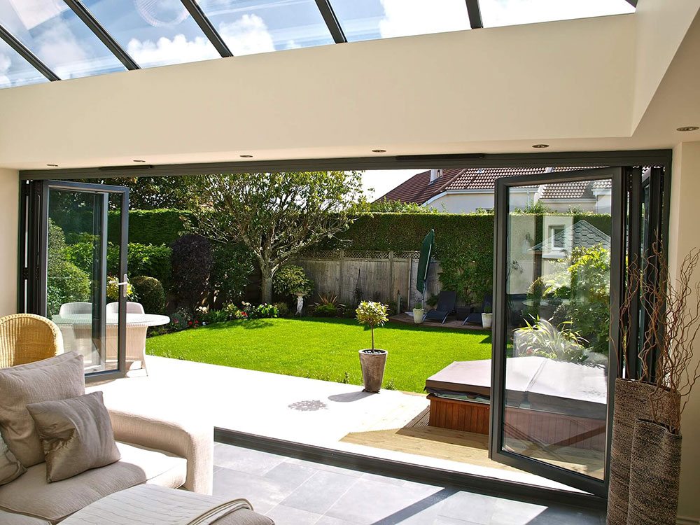 Bi-fold doors fully opened to connect a living space to a landscaped garden