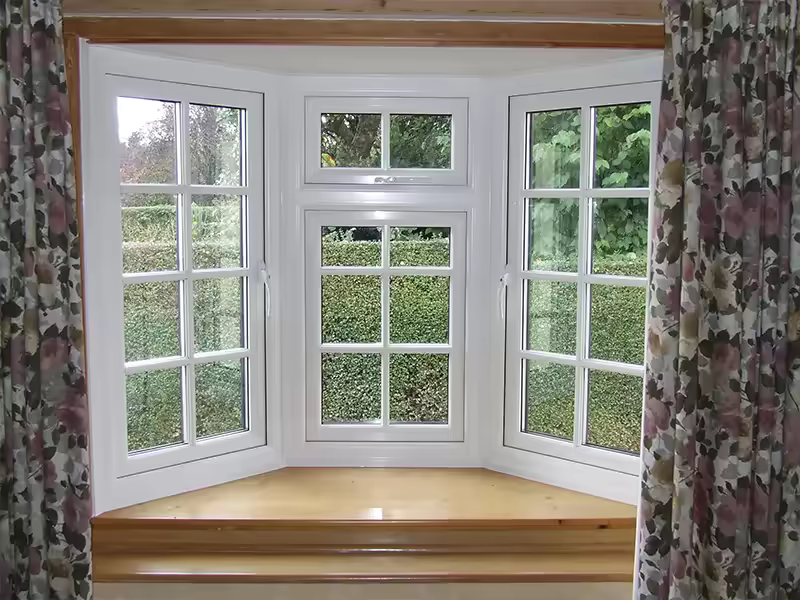 Interior view through a white bow window with garden outlook